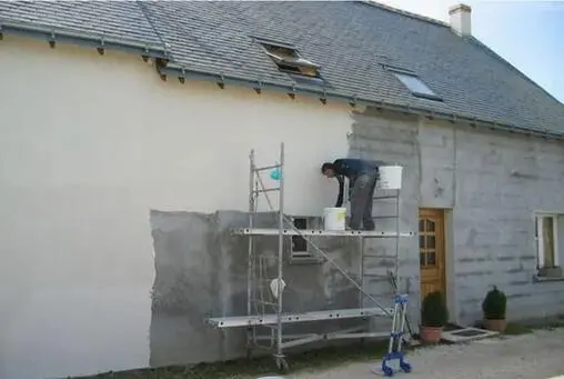 ravalement de façade avec un artisan sur un échafaudage avec un pot de peinture